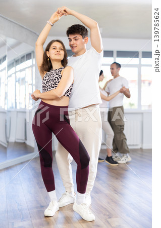 Dance training in group - young men and women dance salsa or bachata in dance studio Dance training in group - young men and women dance salsa or bachata in dance studio 139785624