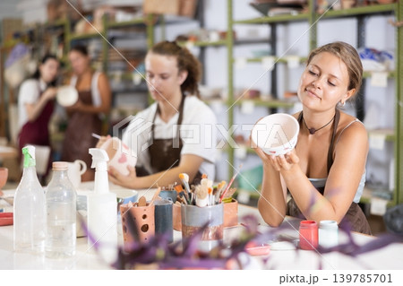 Girl painting with brush on handmade ceramic bowl Girl painting with brush on handmade ceramic bowl 139785701