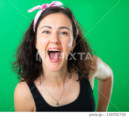 Portrait of adult woman expressing happy emotions on green background 139785730