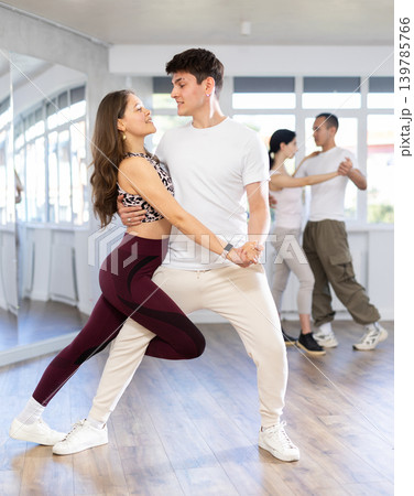 Dance studio - students in casual clothes learn to dance tango Dance studio - students in casual clothes learn to dance tango 139785766