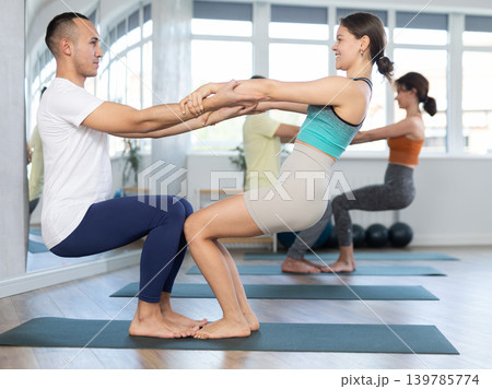Lovers of active lifestyle pair yoga doing double power pair pose in gym 139785774