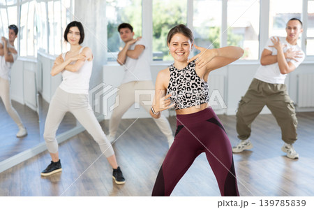 Positive young woman learning modern street dance in studio Positive young woman learning modern street dance in studio 139785839