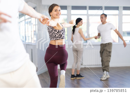 Group of young active sports people practicing rock and roll dance in dance hall 139785851