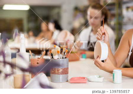 Girls isolated hands paint white ceramic dishes, pottery and blanks Girls isolated hands paint white ceramic dishes, pottery and blanks 139785857