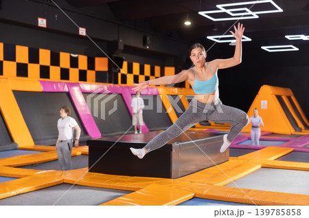 Young woman in sport clothes high jumping in trampoline arena Young woman in sport clothes high jumping in trampoline arena 139785858