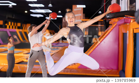 Adult woman playing ball in trampoline center Adult woman playing ball in trampoline center 139785969