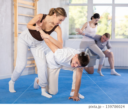 Young woman and guy training self-defense techniques Young woman and guy training self-defense techniques 139786024