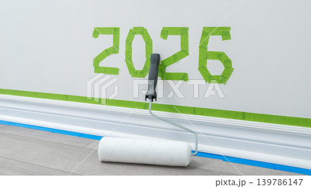 Wall painting project featuring green tape with the number 2026 and a paint roller on a wooden floor in a bright interior setting 139786147