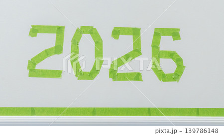 Green painter's tape arranged to form the numbers 2026 on a white wall, showcasing a creative home improvement project Green painter's tape arranged to form the numbers 2026 on a white wall, showcasing a creative home improvement project 139786148