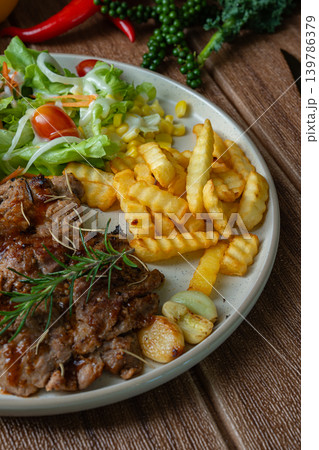 Grilled pork steaks and salad with fries in plate on dark background. Top View 139786379
