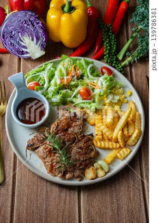 Grilled pork steaks and salad with fries in plate on dark background. Top View Grilled pork steaks and salad with fries in plate on dark background. Top View 139786381