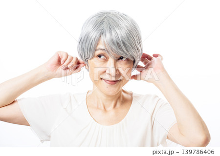 耳をふさいでニヤリと笑う白髪のシニア女性 耳をふさいでニヤリと笑う白髪のシニア女性 139786406