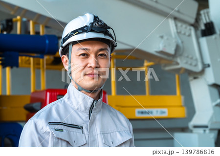 建設車両の前で微笑むヘッドライトをつけた作業着の男性 建設車両の前で微笑むヘッドライトをつけた作業着の男性 139786816