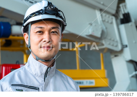 建設車両の前で微笑むヘッドライトをつけた作業着の男性 139786817