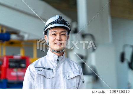 建設車両の前で微笑むヘッドライトをつけた作業着の男性 建設車両の前で微笑むヘッドライトをつけた作業着の男性 139786819