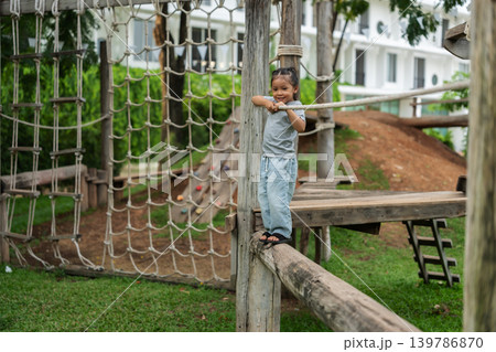 preschool child girl walking on a wooden balancing bridge at outdoor playground preschool child girl walking on a wooden balancing bridge at outdoor playground 139786870