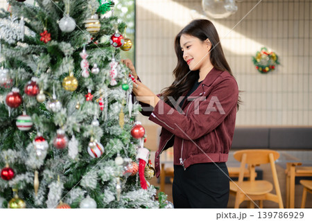 Asian Woman Decorating Christmas Tree at Home | Festive Holiday Lifestyle and Seasonal Celebration Asian Woman Decorating Christmas Tree at Home | Festive Holiday Lifestyle and Seasonal Celebration 139786929