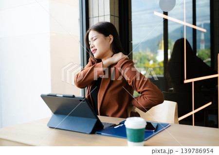 Overworked young Asian businesswoman office worker suffering from neck pain after had a long day at her office desk. office syndrome 139786954