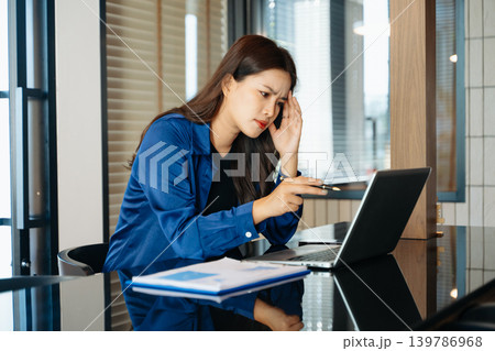 Asian business woman is stressed, bored, and overthinking from working on a tablet at the modern office. Asian business woman is stressed, bored, and overthinking from working on a tablet at the modern office. 139786968