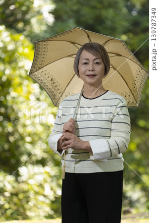 新緑の公園で日傘をさして散歩するシニア女性 139787349