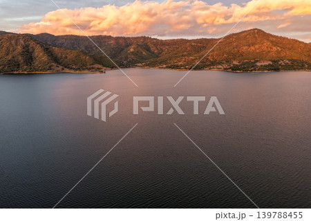 Aerial view of Glenbawn Dam at sunset in NSW Australia. Drone photograph captures calm dam waters, surrounding hills and colourful evening sky reflections from above. Scenic Australian inland 139788455