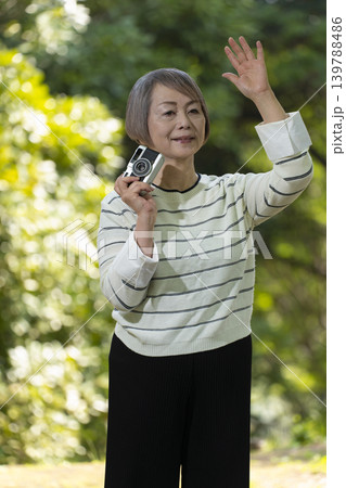 新緑の公園で趣味のカメラで写真を撮るシニア女性 139788486