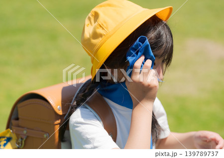 登下校中にタオルで汗を拭う小学生 139789737