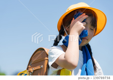 登下校中にタオルで汗を拭う小学生 登下校中にタオルで汗を拭う小学生 139789738