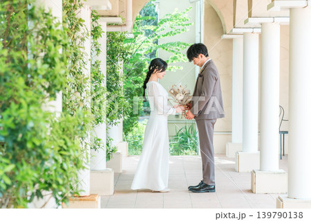 結婚式場でブーケを持って向かい合う新郎新婦(ウェディング・ブライダル・夫婦) 139790138