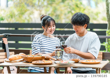 ウッドデッキ,テラス席,バルコニー席で食事するカップル,夫婦(グランピング・ベランピング) ウッドデッキ,テラス席,バルコニー席で食事するカップル,夫婦(グランピング・ベランピング) 139790185