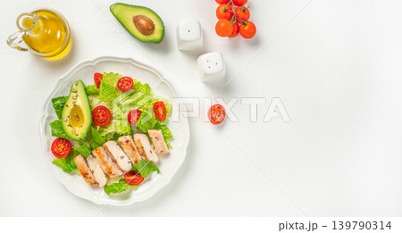 Healthy chicken avocado salad with cherry tomatoes on white background top view Healthy chicken avocado salad with cherry tomatoes on white background top view 139790314