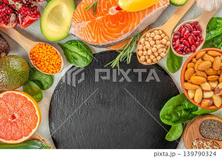 Healthy food background with salmon avocado nuts and superfoods around black stone board Healthy food background with salmon avocado nuts and superfoods around black stone board 139790324