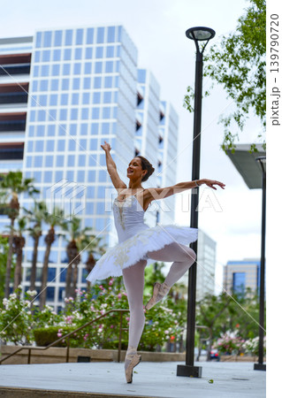 Ballerina leaping in modern city plaza with glass buildings 139790720