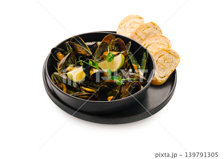 Mussels served with lemon and bread on a black plate 139791305