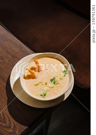 Delicious shrimp soup served in a bowl on a wooden table at a restaurant 139791361