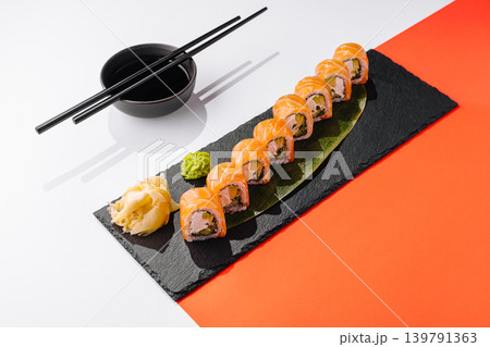 Sushi rolls on black plate with wasabi and ginger on white and red background 139791363