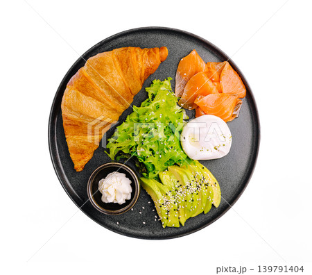 Breakfast plate with croissant, salmon, eggs, and vegetables in black bowl Breakfast plate with croissant, salmon, eggs, and vegetables in black bowl 139791404