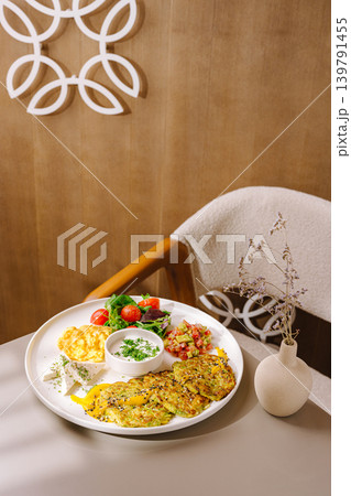 Healthy vegetable pancakes served on a plate on a table in a warm setting Healthy vegetable pancakes served on a plate on a table in a warm setting 139791455