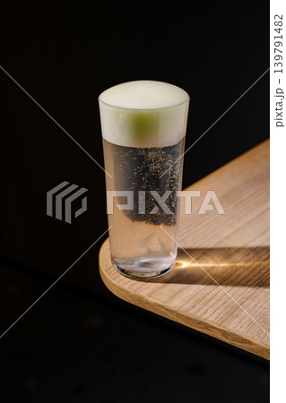 Refreshing drink with foam on a wooden table in a dark room Refreshing drink with foam on a wooden table in a dark room 139791482