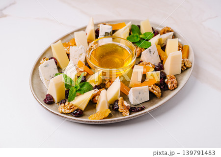 Cheese and nut platter with honey served on a round plate for snack time 139791483