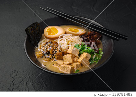 Delicious bowl of ramen with noodles and toppings served in a black bowl Delicious bowl of ramen with noodles and toppings served in a black bowl 139791492