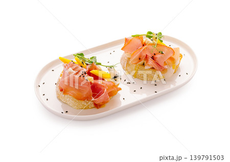 Fresh bread topped with ham and mango on a white plate 139791503