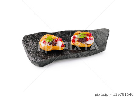 Delicious small canapes served on black stone plate with toppings Delicious small canapes served on black stone plate with toppings 139791540