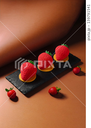 Strawberry desserts arranged on a black plate with small berries around Strawberry desserts arranged on a black plate with small berries around 139791541