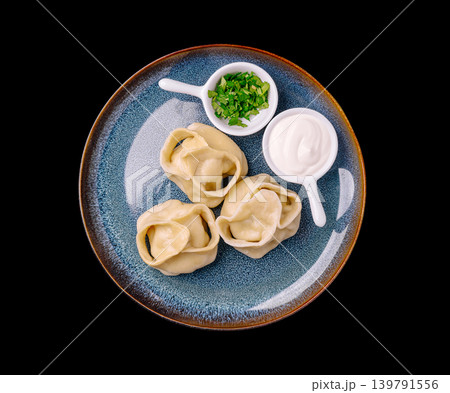 Dumplings served with sour cream and herbs on a blue plate in a kitchen 139791556