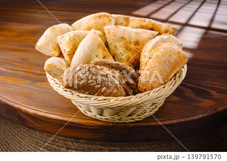 Variety of bread placed in basket on wooden table during late morning Variety of bread placed in basket on wooden table during late morning 139791570