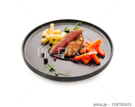 Gourmet duck dish served on a dark plate with colorful vegetables and sauce Gourmet duck dish served on a dark plate with colorful vegetables and sauce 139791621