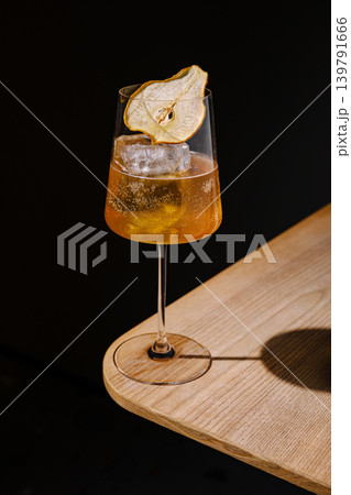 Cocktail served on a wooden table with dried fruit garnish in a bar scene 139791666