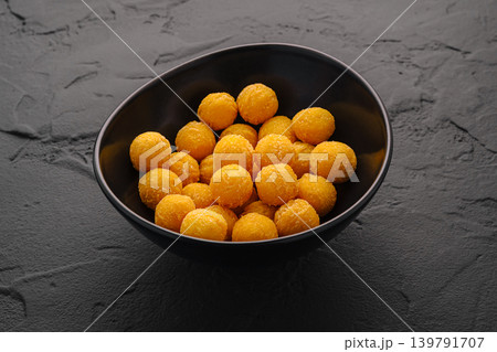 Snack balls in a black bowl on a textured surface at a kitchen table Snack balls in a black bowl on a textured surface at a kitchen table 139791707