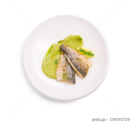 Fresh fish served with green puree and lemon butter on a white plate 139791729